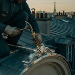 Gros plan sur un couvreur travaillant sur un ornement de toiture parisienne, la Tour Eiffel en arrière-plan au coucher du soleil.